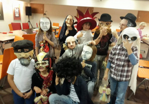 Uczniowie w różnych maskach teatralnych.