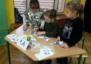 Reprezentanci klasy 1A- Patryk, Natalia, Marianna układają z puzzli znak drogowy