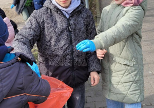 Uczniowie kl. II c sprzątają okolice parkingu.